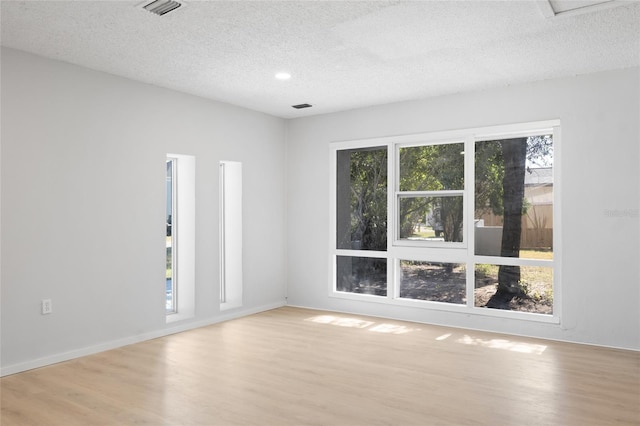 spare room with light wood-type flooring and a textured ceiling