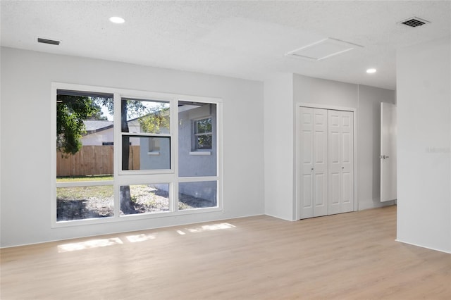 unfurnished room with a textured ceiling and light hardwood / wood-style flooring