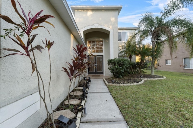 entrance to property with a lawn and stucco siding