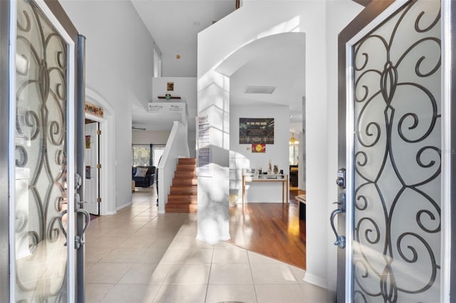 entryway with tile patterned floors, stairway, arched walkways, and visible vents