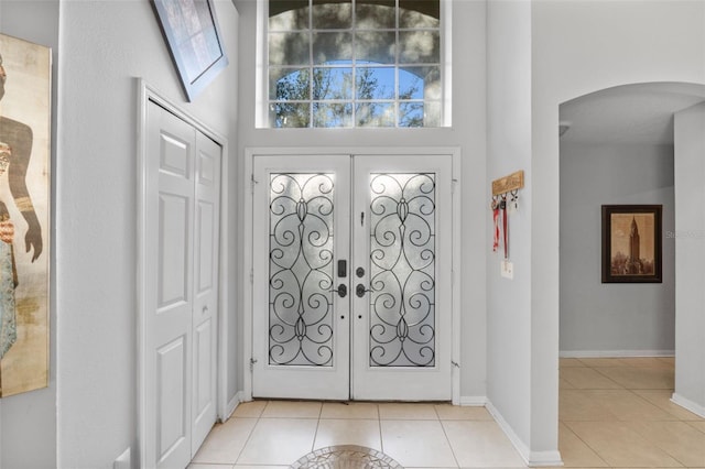 tiled foyer featuring french doors and a towering ceiling