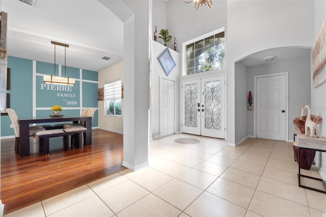 foyer entrance featuring a chandelier, light hardwood / wood-style floors, a high ceiling, and french doors