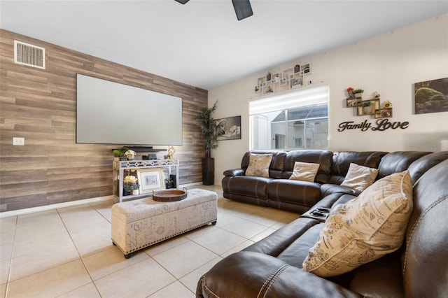 living room featuring ceiling fan, wood walls, and light tile patterned floors