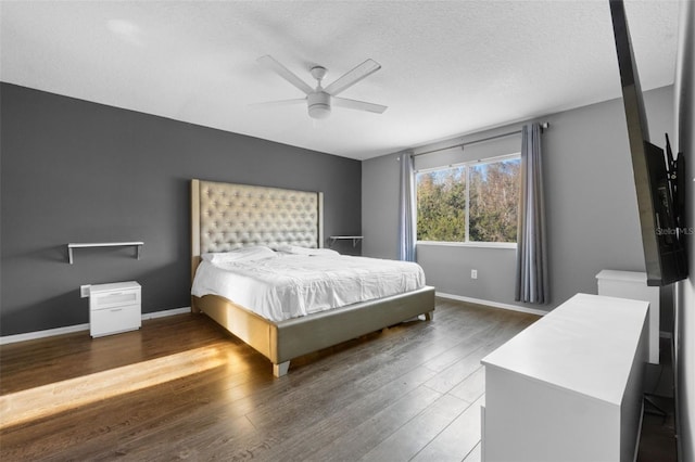 bedroom with ceiling fan, dark wood-type flooring, and a textured ceiling