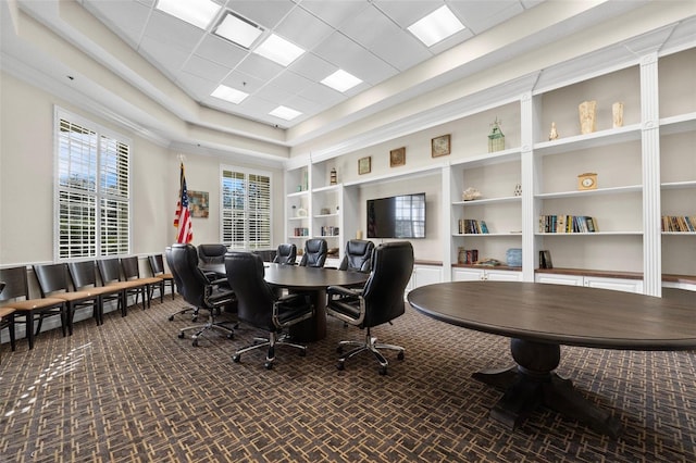 office space featuring built in shelves, a drop ceiling, and dark carpet