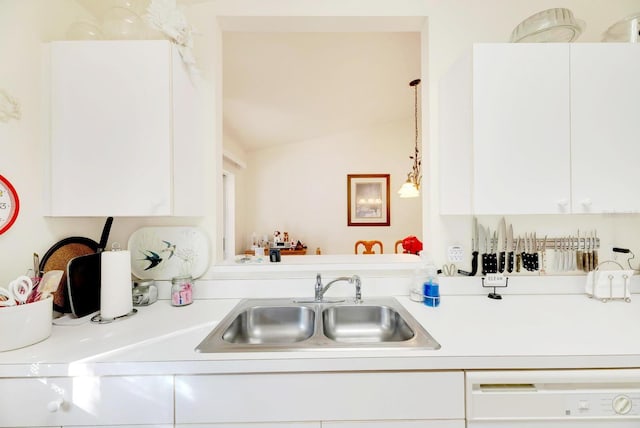 kitchen with white dishwasher, vaulted ceiling, sink, decorative light fixtures, and white cabinetry