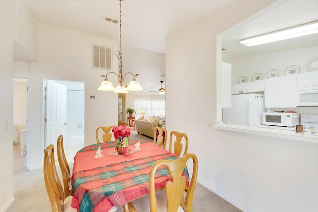 dining area with ceiling fan with notable chandelier and light colored carpet