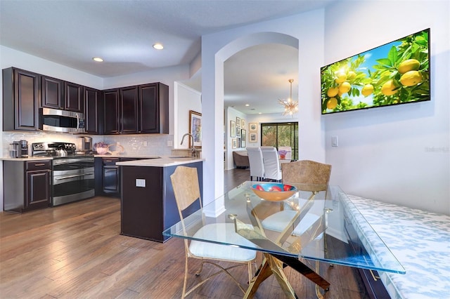 kitchen with appliances with stainless steel finishes, hardwood / wood-style flooring, tasteful backsplash, and sink