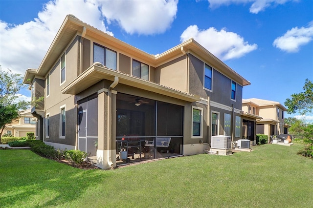 rear view of property with a lawn, a sunroom, and central AC unit