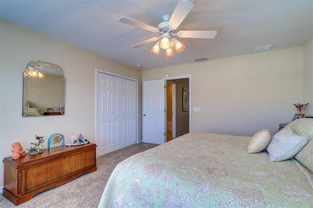 carpeted bedroom featuring ceiling fan, a closet, and a textured ceiling