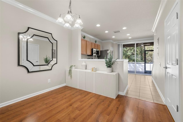 kitchen featuring a chandelier, crown molding, light hardwood / wood-style floors, and appliances with stainless steel finishes