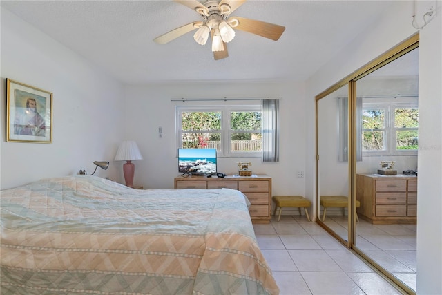 tiled bedroom with ceiling fan, a textured ceiling, and a closet