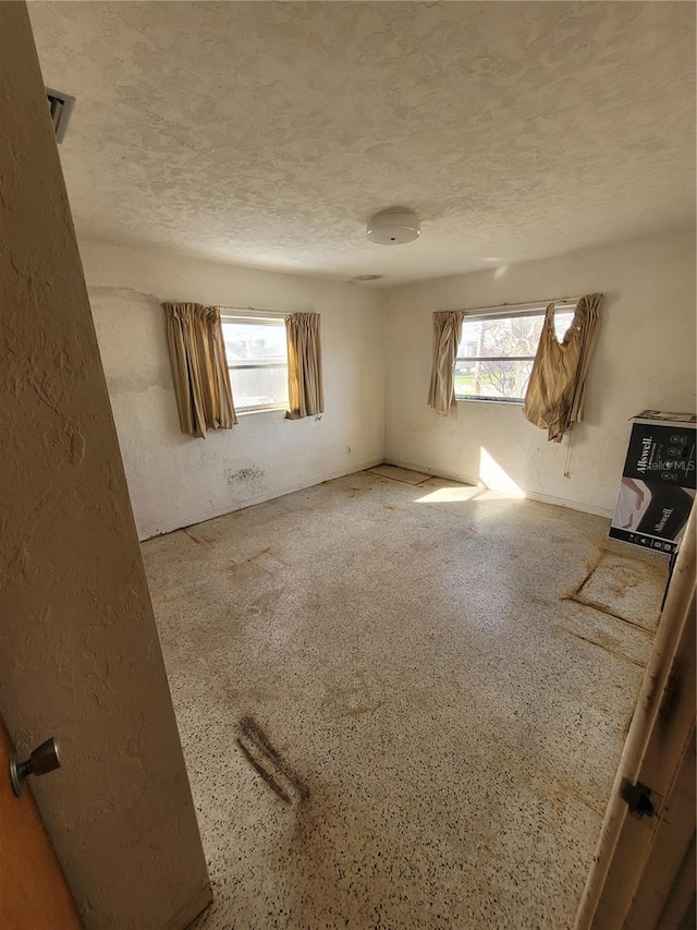 unfurnished room with a healthy amount of sunlight and a textured ceiling