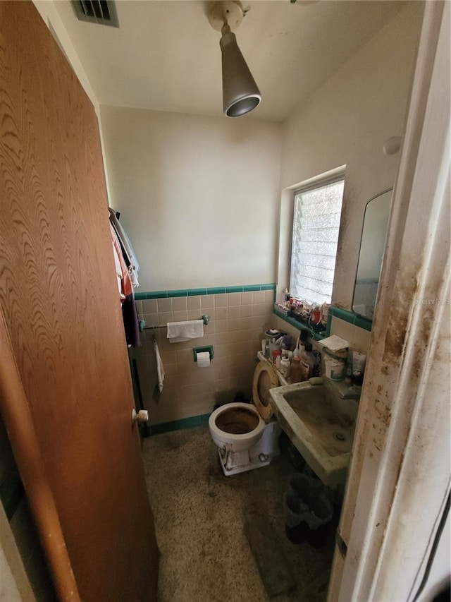 bathroom featuring sink, tile walls, and toilet