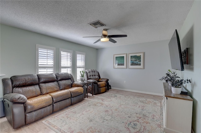 living room with ceiling fan, light hardwood / wood-style floors, and a textured ceiling