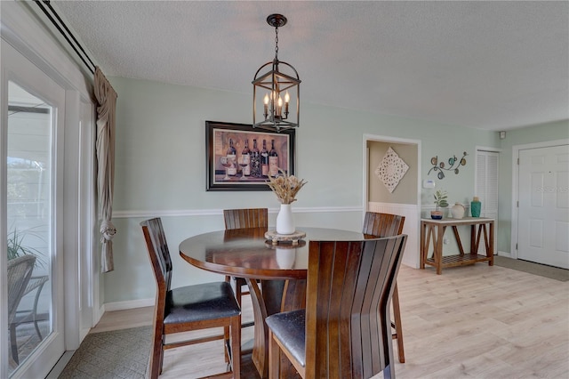 dining room with a chandelier, light hardwood / wood-style floors, and a textured ceiling