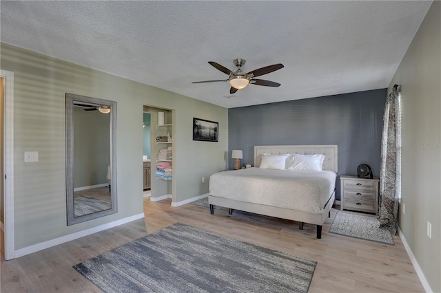 bedroom with ceiling fan, light wood-type flooring, and a textured ceiling