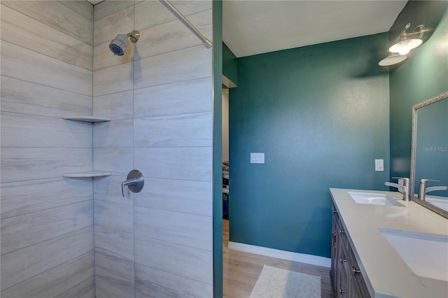 bathroom with tiled shower, vanity, and hardwood / wood-style flooring