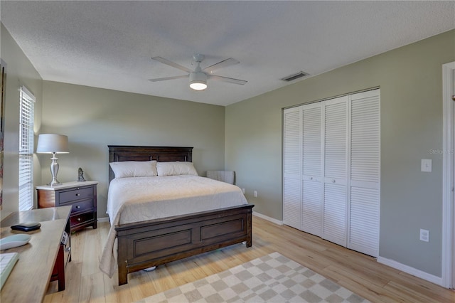 bedroom featuring a textured ceiling, light wood-type flooring, a closet, and ceiling fan