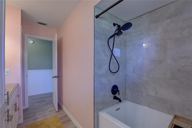 bathroom featuring hardwood / wood-style floors, vanity, and tiled shower / bath combo