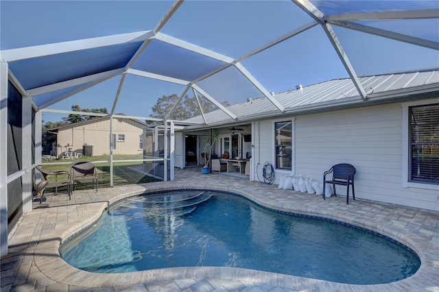 view of pool with a patio, glass enclosure, and ceiling fan