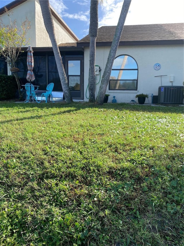 rear view of house with cooling unit and a yard