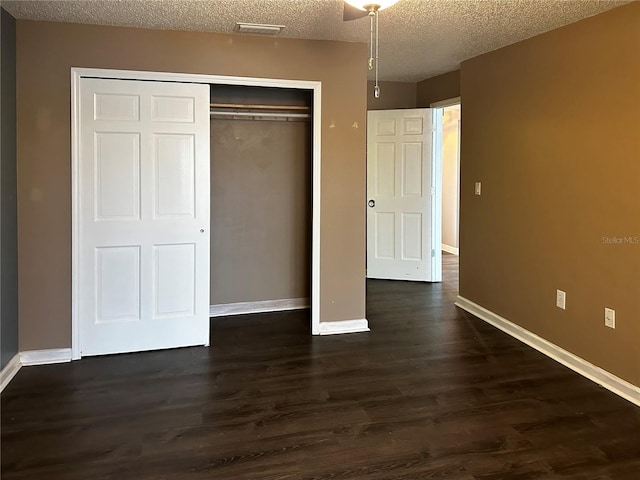 unfurnished bedroom with dark hardwood / wood-style floors, a textured ceiling, and a closet