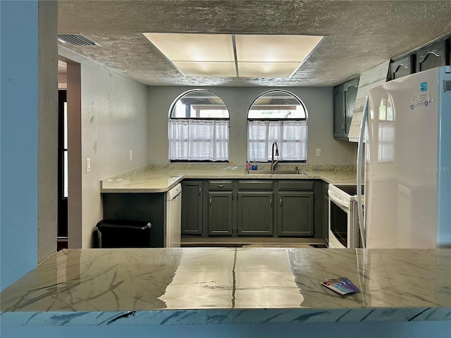 kitchen featuring a textured ceiling, sink, and white appliances