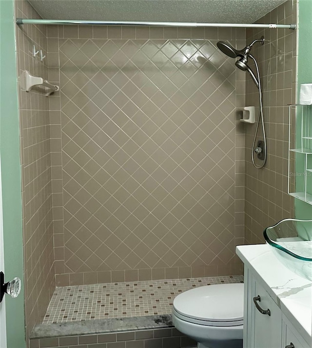 bathroom featuring tiled shower, a textured ceiling, vanity, and toilet