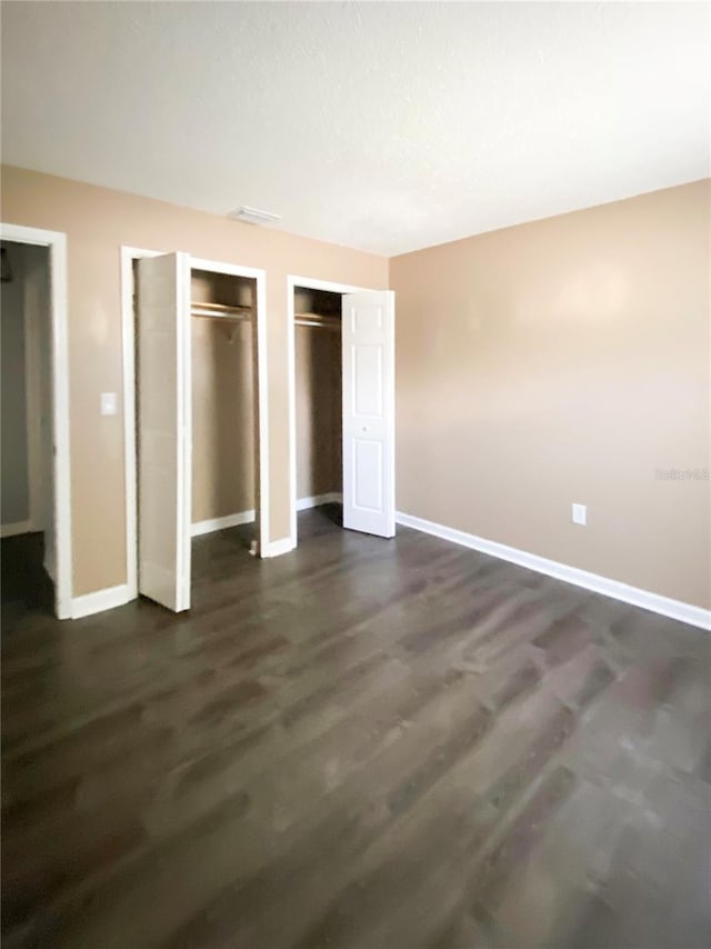 9107 Lingrove Rd, Weeki Wachee, FL 34613 - unfurnished bedroom with dark wood-style flooring, multiple closets, and baseboards