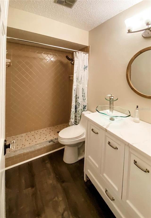 9107 Lingrove Rd, Weeki Wachee, FL 34613 - full bath featuring a textured ceiling, wood finished floors, vanity, and a tile shower
