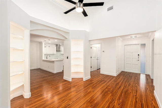 unfurnished living room featuring crown molding, dark hardwood / wood-style flooring, ceiling fan, and sink