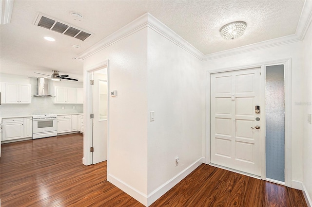 foyer with a textured ceiling, ornamental molding, and dark wood-type flooring