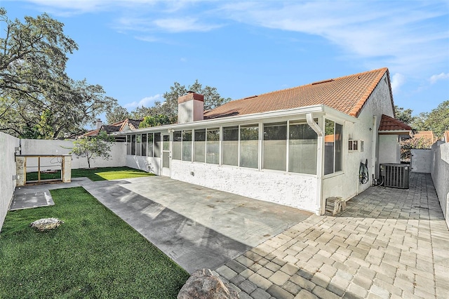 back of house with a lawn, a sunroom, cooling unit, and a patio