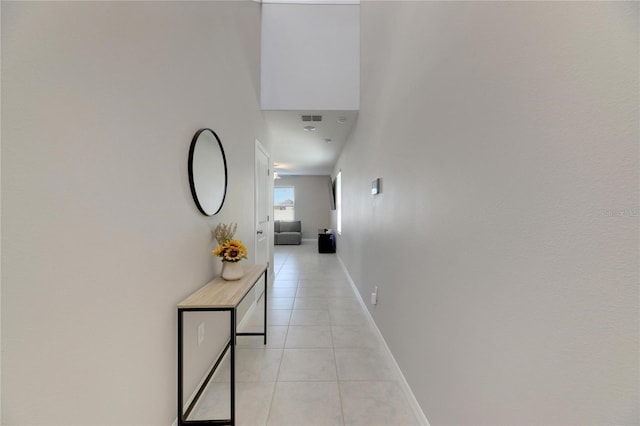 corridor featuring a towering ceiling and light tile patterned flooring