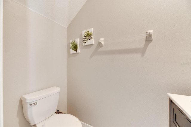 bathroom featuring vanity, toilet, and lofted ceiling