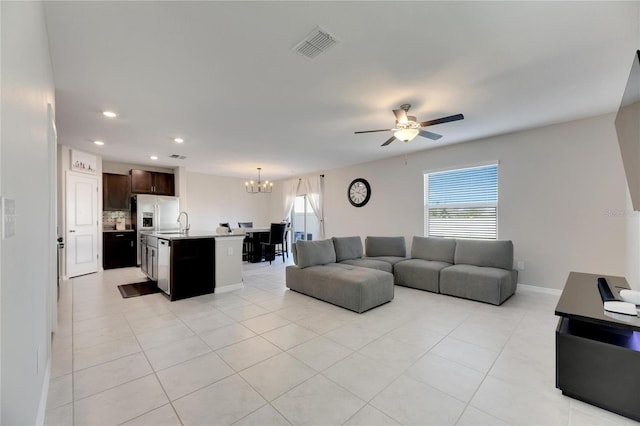 tiled living room with ceiling fan with notable chandelier and sink