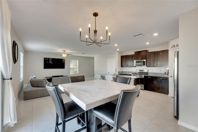 tiled dining room with ceiling fan with notable chandelier and a healthy amount of sunlight