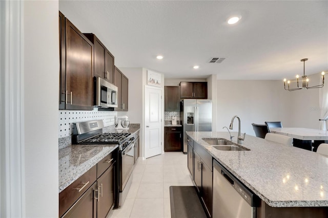 kitchen featuring sink, stainless steel appliances, a notable chandelier, an island with sink, and light tile patterned floors