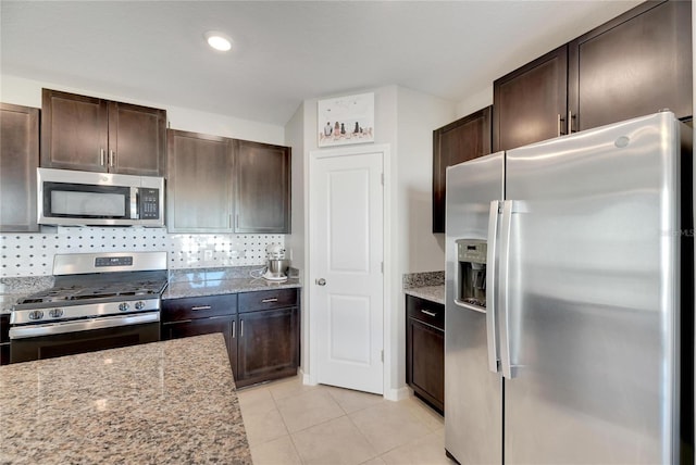 kitchen featuring backsplash, dark brown cabinets, light stone counters, and stainless steel appliances