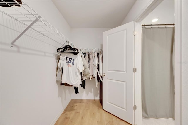 walk in closet with light hardwood / wood-style floors