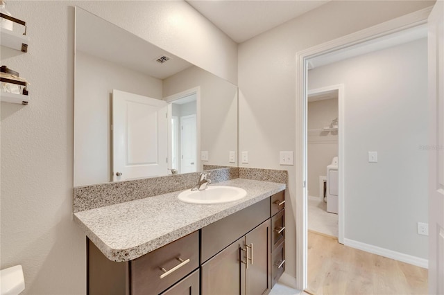 bathroom with washer / clothes dryer, vanity, and hardwood / wood-style flooring