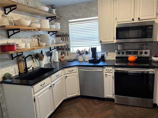 kitchen featuring dark parquet flooring, white cabinets, sink, decorative backsplash, and stainless steel appliances