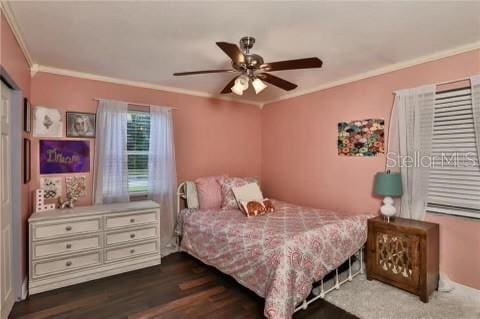 bedroom featuring dark hardwood / wood-style flooring, ceiling fan, and crown molding