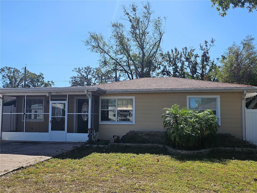 view of front of home with a front yard and a sunroom