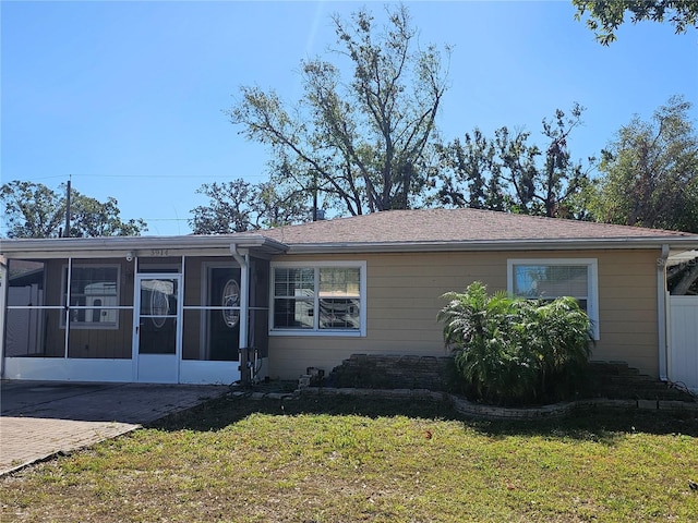 view of front of home with a front yard and a sunroom