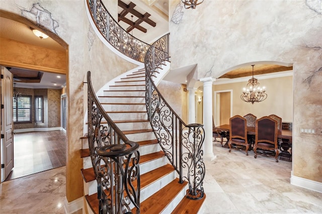 staircase featuring beam ceiling, coffered ceiling, decorative columns, crown molding, and a chandelier