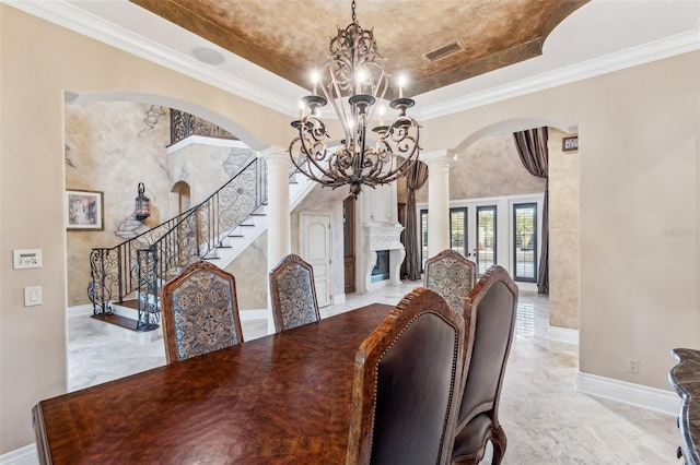 dining space featuring a chandelier, a tray ceiling, ornate columns, and ornamental molding