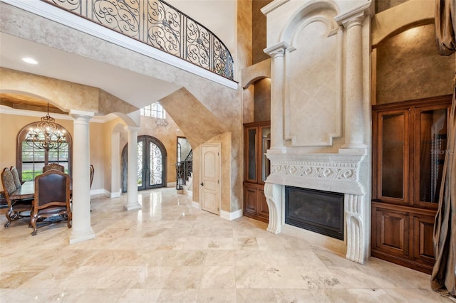 foyer featuring crown molding, french doors, a towering ceiling, and a chandelier