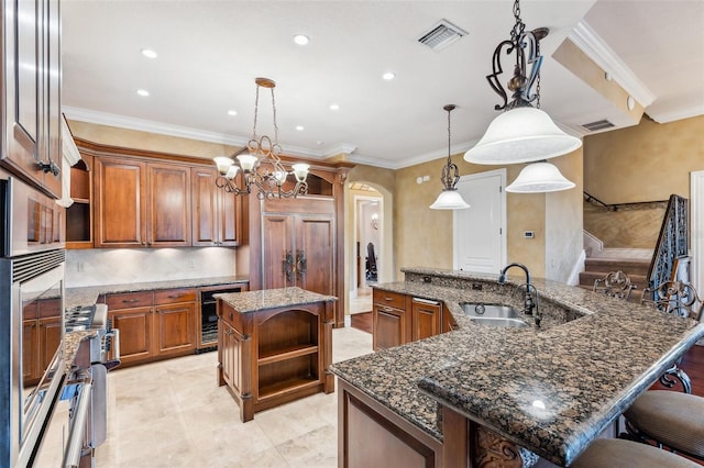 kitchen with a spacious island, sink, crown molding, hanging light fixtures, and beverage cooler